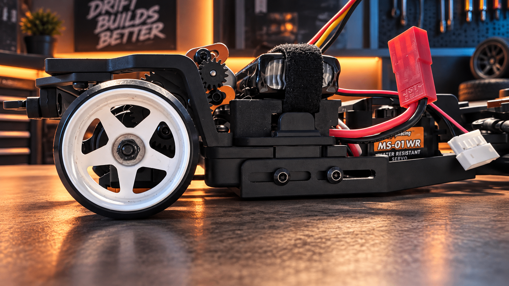 Close side view of the HPI chassis with a white wheel and the main chassis plate sitting low over the workbench