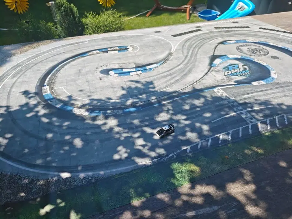 Geschwungene RC-Driftstrecke im Tageslicht mit Schatten von Bäumen