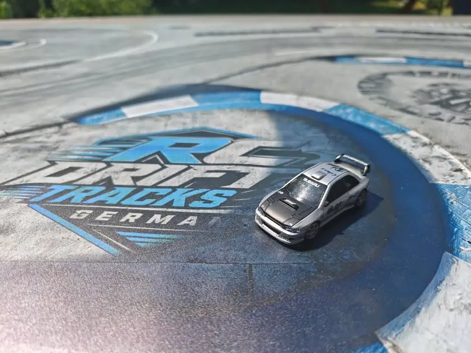 Silbernes RC-Driftauto auf einer blauen Kurve mit Streckenlogo