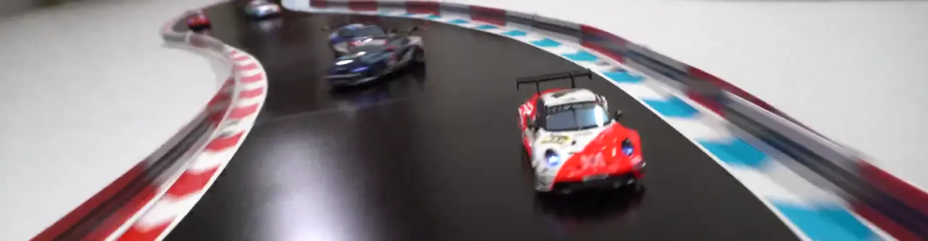 Mehrere Modellfahrzeuge hintereinander in einer langen Kurve